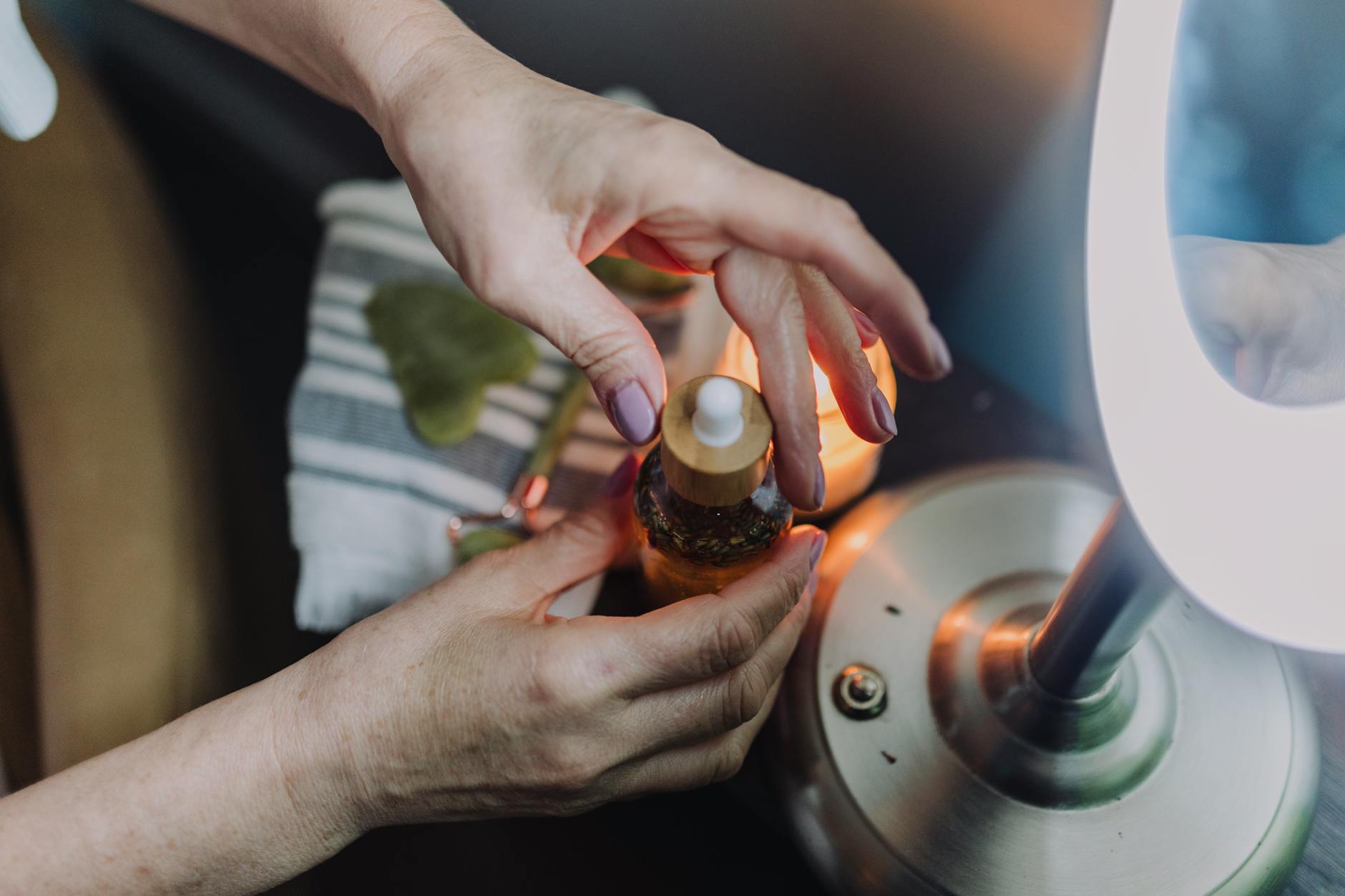 Dłonie trzymające butelkę kosmetyku w ciepłym, domowym świetle lampy