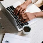 Osoba pisze pierwszy wpis na blogu przy laptopie w kawiarni