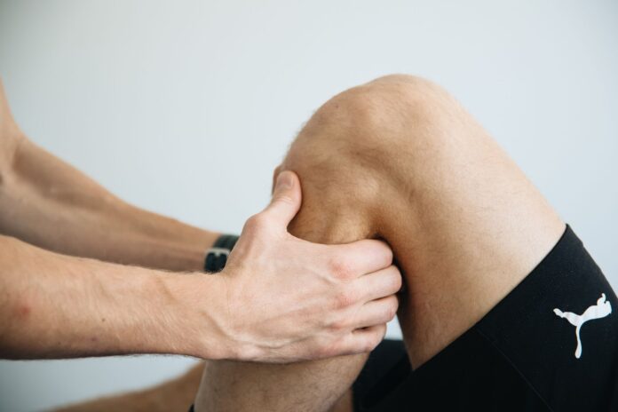 Masaż kolana podczas zabiegu fizjoterapeutycznego